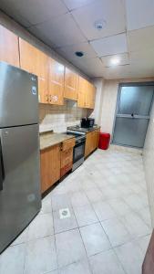 a kitchen with wooden cabinets and a stainless steel refrigerator at Double window Partition Room in Tecom Near Metro in Dubai