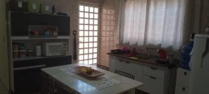 a kitchen with a sink and a table with a microwave at Quarto Divas na Sakura House in Indaiatuba