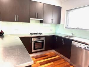 a kitchen with brown cabinets and a stainless steel oven at Adelaide Dress Circle Apartments - Archer Street in Adelaide