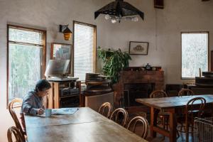 un hombre sentado en una mesa leyendo un periódico en Pension FOLKLORE en Suginosawa