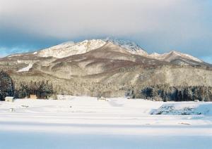 a snow covered mountain range with a snow covered field at Pension FOLKLORE in Suginosawa