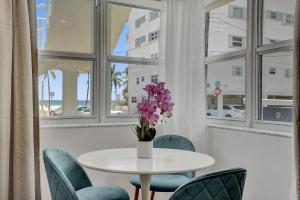 une table avec des chaises et un vase avec des fleurs violettes dans l'établissement Marine Villas # 1, à Hollywood