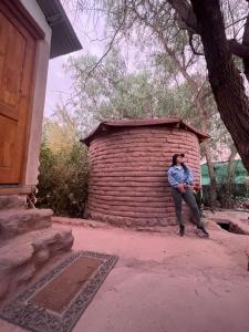 a man sitting on the side of a brick wall at Cabañas San Pedro de Atacama. in San Pedro de Atacama