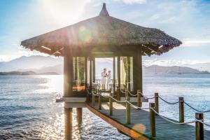 una pareja de pie en un muelle en el agua en Vinpearl Luxury Nha Trang en Nha Trang