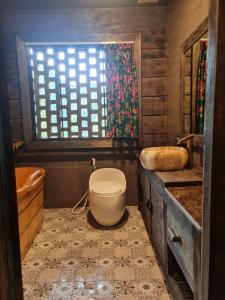 ein Bad mit einem WC, einem Waschbecken und einem Fenster in der Unterkunft Quan Din Ngai Villa in Dồng Văn