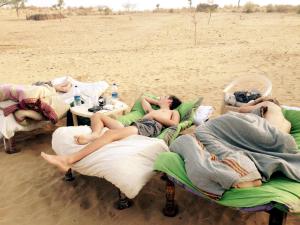 a group of people laying on beds on the beach at Madhu Singh Dhani Home Stay -Ridmalsar in Champasar