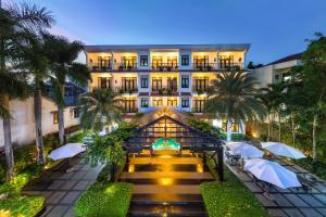 a hotel with umbrellas in front of a building at Hadana Boutique Resort HoiAn - former Belle Maison Hadana HoiAn in Hoi An