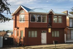 una casa de ladrillo rojo con puerta blanca en Haiken Hostal en Punta Arenas
