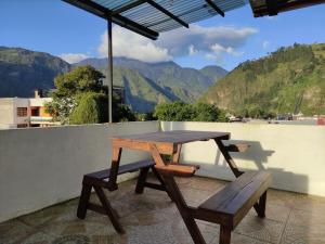 una mesa de picnic de madera y un banco en un balcón con montañas en Apartamento "ROOFTOP view 360", en Baños