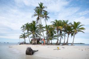 eine Gruppe von Menschen, die am Strand mit Palmen stehen in der Unterkunft San Blas Sailing Experience With Us! in El Porvenir