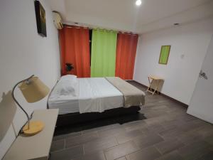 Habitación con cama y cortina colorida en Casa Escalante Hostel en San José