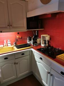 una cocina con armarios blancos y azulejos rojos en La Maison d'Yvonne, en La Bouille