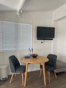 a dining room table with two chairs and a television at Pickmere Waters in Kerikeri