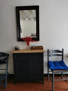 een spiegel aan een muur met een stoel en een tafel bij La Maison d'Yvonne in La Bouille