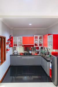 a large kitchen with red cabinets and appliances at Homestay Simply Homy Jogja dekat Ambarukmo plaza in Yogyakarta