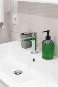 a bathroom sink with a green soap dispenser on it at RentWill apartments Double in Chişinău