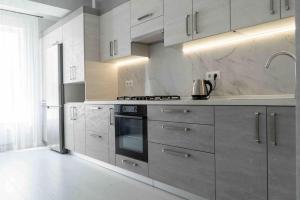 a kitchen with white cabinets and a stove top oven at RentWill apartments Double in Chişinău