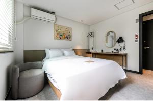 a bedroom with a large white bed and a chair at Hotel No. 25 Gyeongju bus terminal in Gyeongju