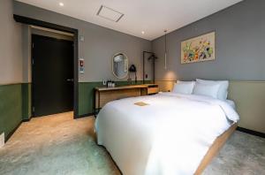 een slaapkamer met een groot wit bed en een spiegel bij Hotel No. 25 Gyeongju bus terminal in Gyeongju
