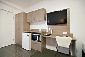 W kuchni znajduje się biurko, kuchenka mikrofalowa i lodówka. w obiekcie The Aberdeen Motel w mieście Dubbo