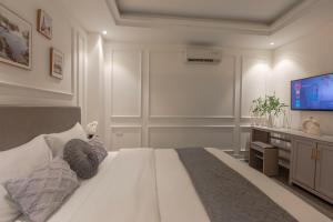 a bedroom with a large white bed and a flat screen tv at Keypad Hotel - 87 Nguyễn Khang in Hanoi