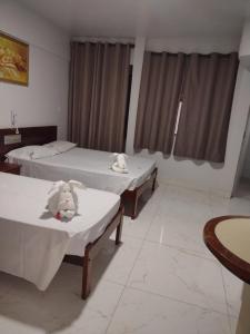 a room with two beds and two tables in it at Araras CTC Apart Service in Caldas Novas