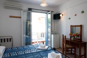 a bedroom with a bed and a desk and a window at Hotel Kyma in Skala Eresou