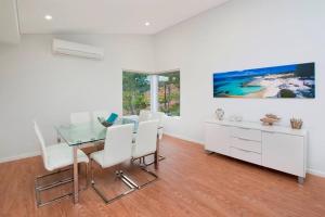Un comedor con una mesa de cristal y sillas blancas. en GeoVista @ Cape Villas Dunsborough, en Dunsborough