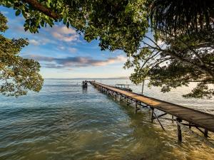 a pier stretches out into the water on a lake at Scuba Republic Beach Bungalows in Tapokreng