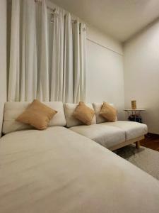 - un salon avec un canapé blanc et des rideaux dans l'établissement Hidden Gem Bali Stays in KL, à Kuala Lumpur