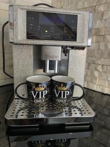een koffiezetapparaat met 2 koffiemokken en een tv bij VIP Haus Winterberg in Winterberg