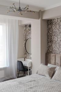 a bedroom with a bed and a desk with a mirror at RentWill apartments Diplomat in Chişinău