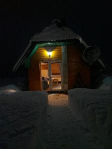 a small house in the snow at night at Durmitor Bungalows in Žabljak