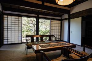 鎌倉市にある甘糟屋敷 Amakasu Yashiki KAMAKURAのテーブルと椅子、窓が備わる客室です。
