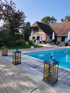 3 linternas en una terraza de madera junto a una piscina en Léalie, en Gonneville-sur-Honfleur