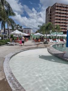 una gran piscina de agua con sillas y un edificio en Araras CTC Apart Service, en Caldas Novas