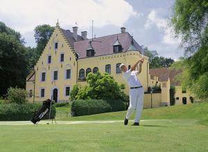 a man is playing golf in front of a house at Apartment Haus Maria Waldblick in Burtenbach
