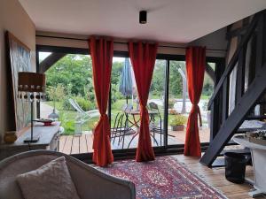 a living room with red curtains and a sliding glass door at Léalie in Gonneville-sur-Honfleur