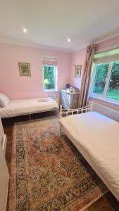 a bedroom with two beds and a rug at Magnolia Cottage - Kent in Lyminge