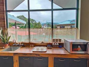 eine Küchentheke mit einer Mikrowelle und einem großen Fenster in der Unterkunft Aviator's Bungalow - Dharamshala in Dharamshala