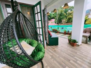 a hammock on a house with a swimming pool at Aviator's Bungalow - Dharamshala in Dharamshala