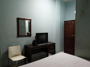 a bedroom with a desk with a tv and a chair at OYO 93046 Hotel Fortuna Parepare in Parepare