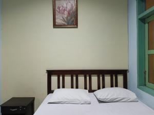 un letto con due cuscini e una foto sul muro di OYO 93046 Hotel Fortuna Parepare a Parepare