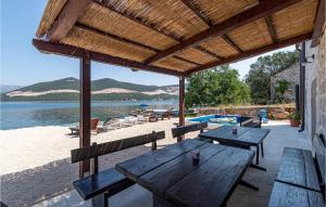 een picknicktafel op het strand met uitzicht op het water bij Pet Friendly Home In Putnikovic With Kitchen in Putniković