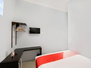 a bedroom with a bed and a tv on the wall at OYO 3160 Guesthouse Pagi Sore Syariah in Padang