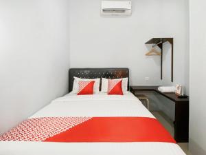 a bedroom with a red and white bed and a desk at OYO 3160 Guesthouse Pagi Sore Syariah in Padang