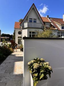 埃肯弗德的住宿－Villa am Strand，房屋旁的白色墙,有盆栽