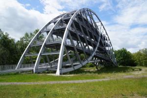 a metal bridge in a park with a grass field at Entspannen am Großen Goitzschesee inkl. Netflix in Holzweißig