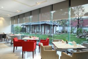 a restaurant with tables and chairs and a large window at Holiday Inn Beijing Deshengmen by IHG on 2nd Ring Road Extension 10-15 minute taxi ride to Shichahai Lama Temple Drum Tower Close to Beijing North Station for Badaling Great Wall Near Exit B Jishuitan Metro Line 2 in Beijing