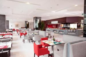 un restaurante con mesas blancas y sillas rojas en Holiday Inn Beijing Deshengmen, an IHG Hotel en Pekín